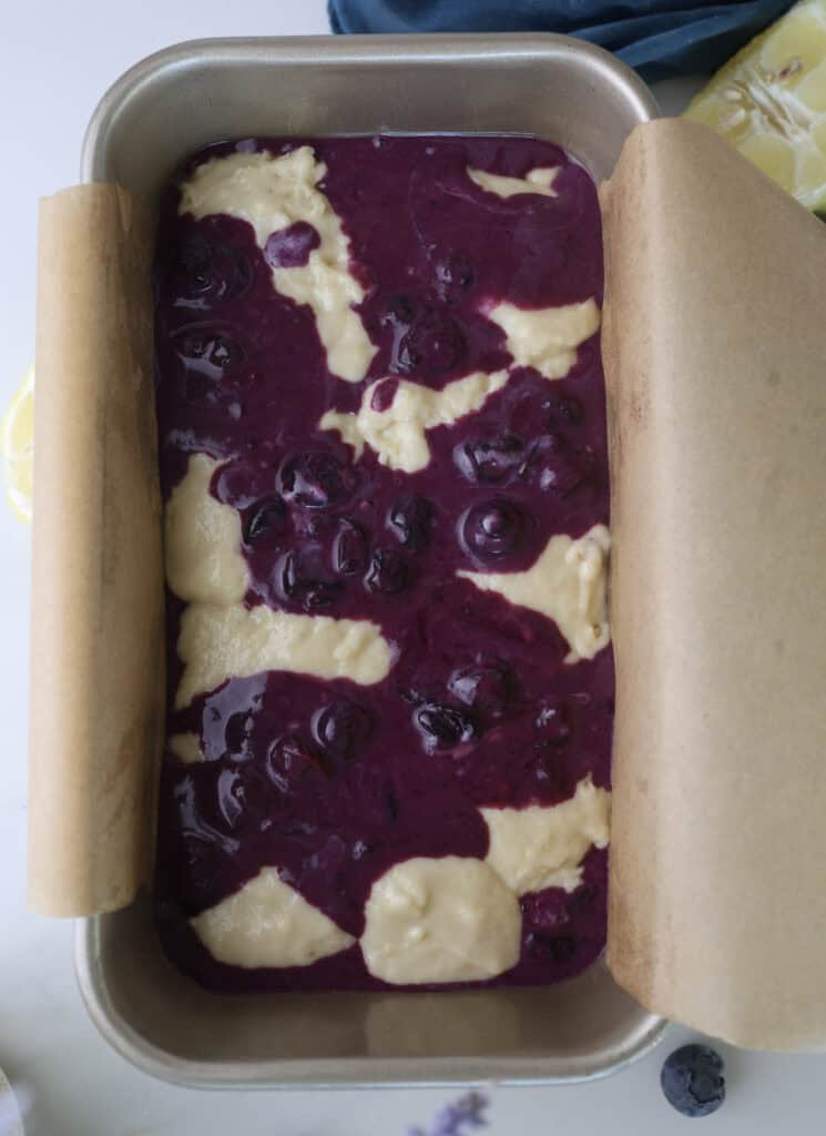 Lemon blueberry swirl loaf cake in bread pan prior to baking.