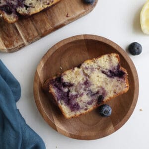 Lemon blueberry swirl loaf cake slice on a wood plate.