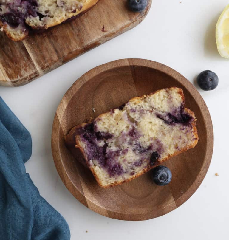 Lemon blueberry swirl loaf cake slice on a wood plate.