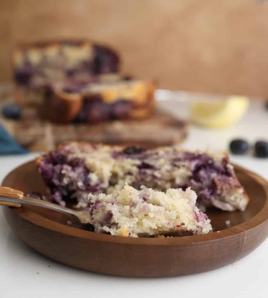 Slice of lemon blueberry swirl loaf on a plate with a fork holding a piece.
