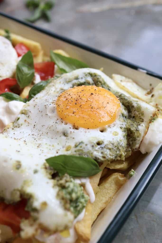 Up close shot of the pesto fried egg over caprese breakfast fries. 