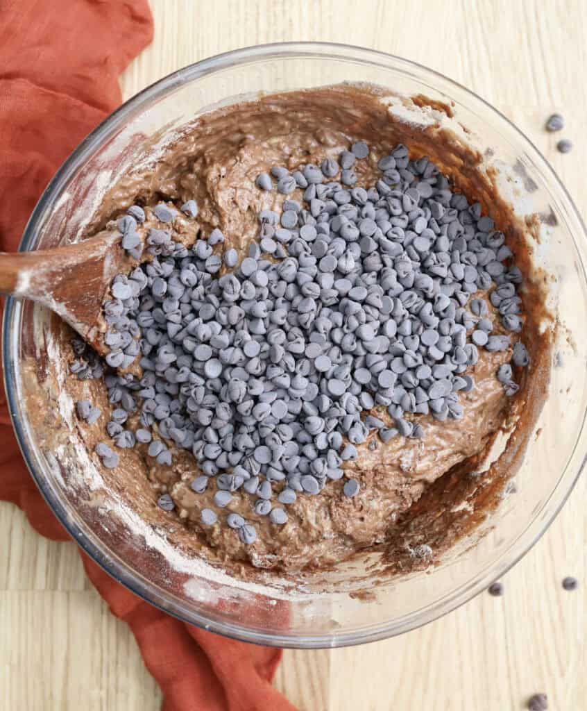 Double chocolate zucchini muffin batter in a bowl with chocolate chips. 