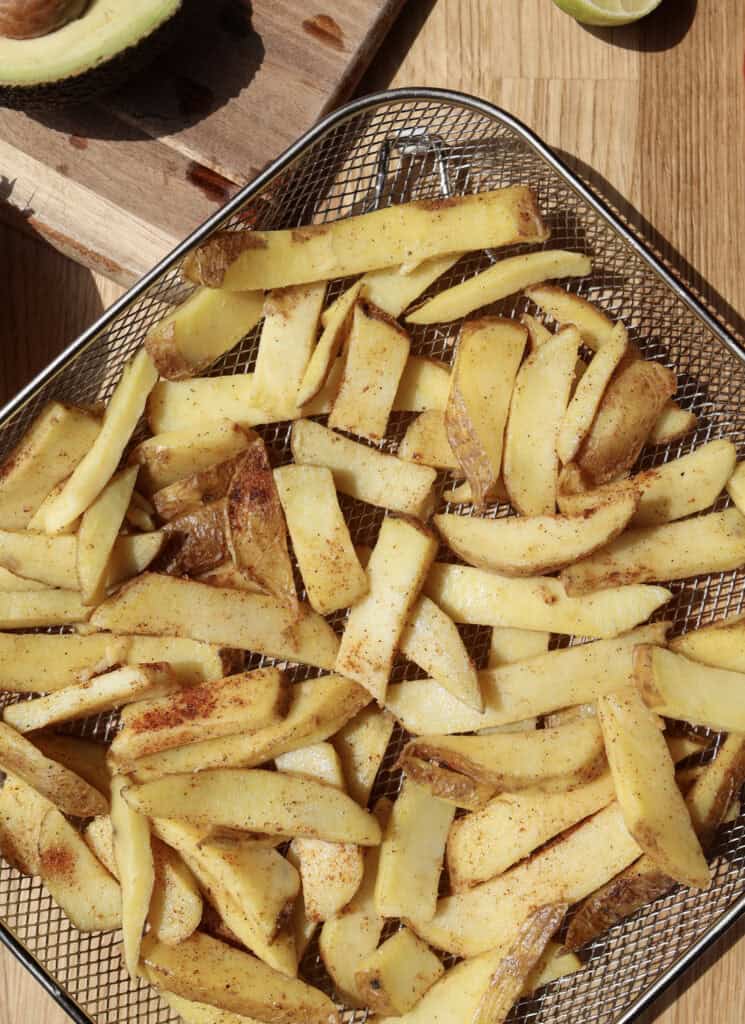 Seasoned French Fries in air fryer pan for the loaded breakfast fries.