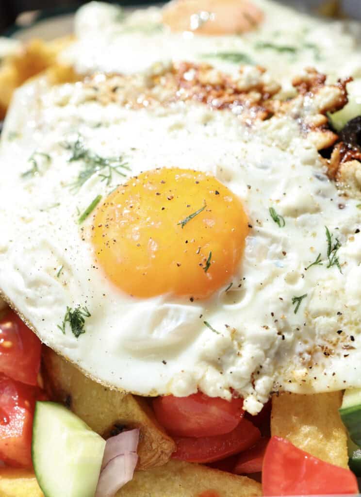 Up close shot of the feta fried egg over the Mediterranean breakfast fries.