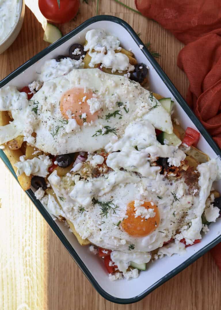 Loaded Mediterranean breakfast fries with feta fried eggs on a serving plate.