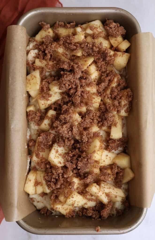Apple fritter batter with cinnamon apples and streusel on top before being baked in the oven. 