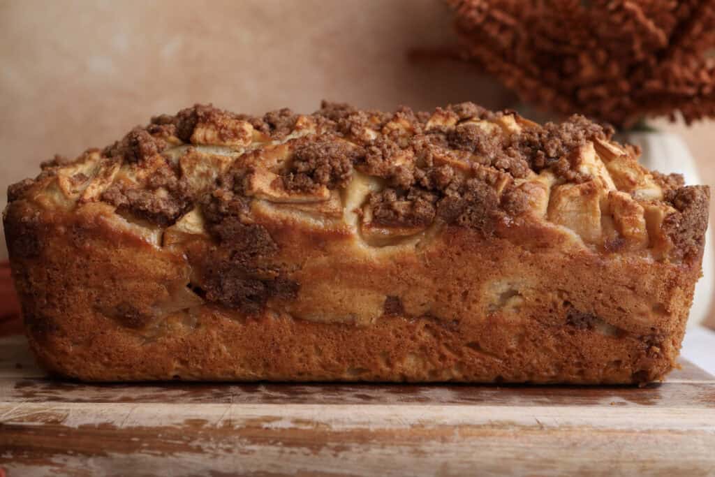 Side view of the apple fritter bread without the glaze sitting on a cutting board. 