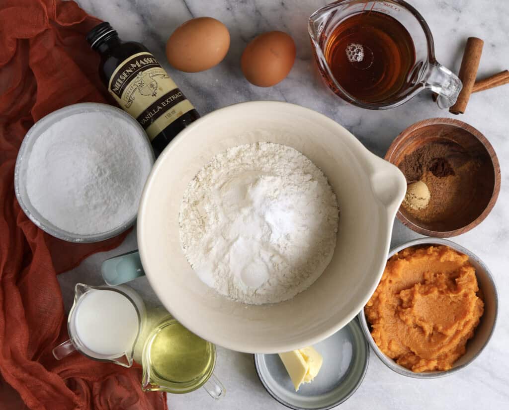 All the ingredients for the baked pumpkin donuts with maple icing sitting on the counter.