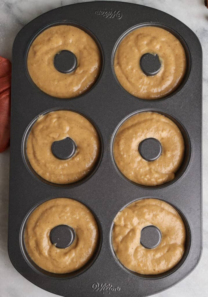 Pumpkin donut batter in a donut pan before being baked.