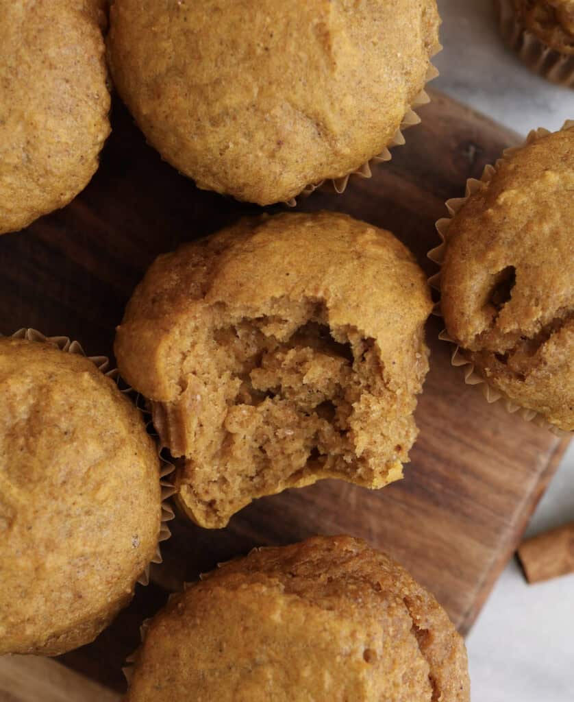 Cottage cheese pumpkin muffin with a bite sitting on a cutting board.