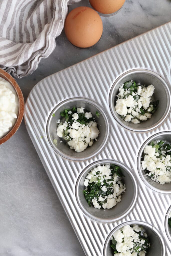 Spinach, sautéed onions, and feta cheese in a muffin tins.