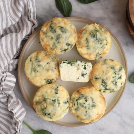 Cottage cheese egg bites on a plate with on in the middle cut open.