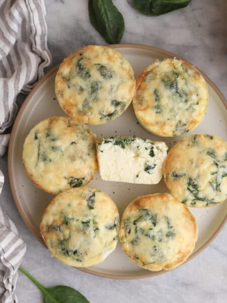 Cottage cheese egg bites on a plate with on in the middle cut open.