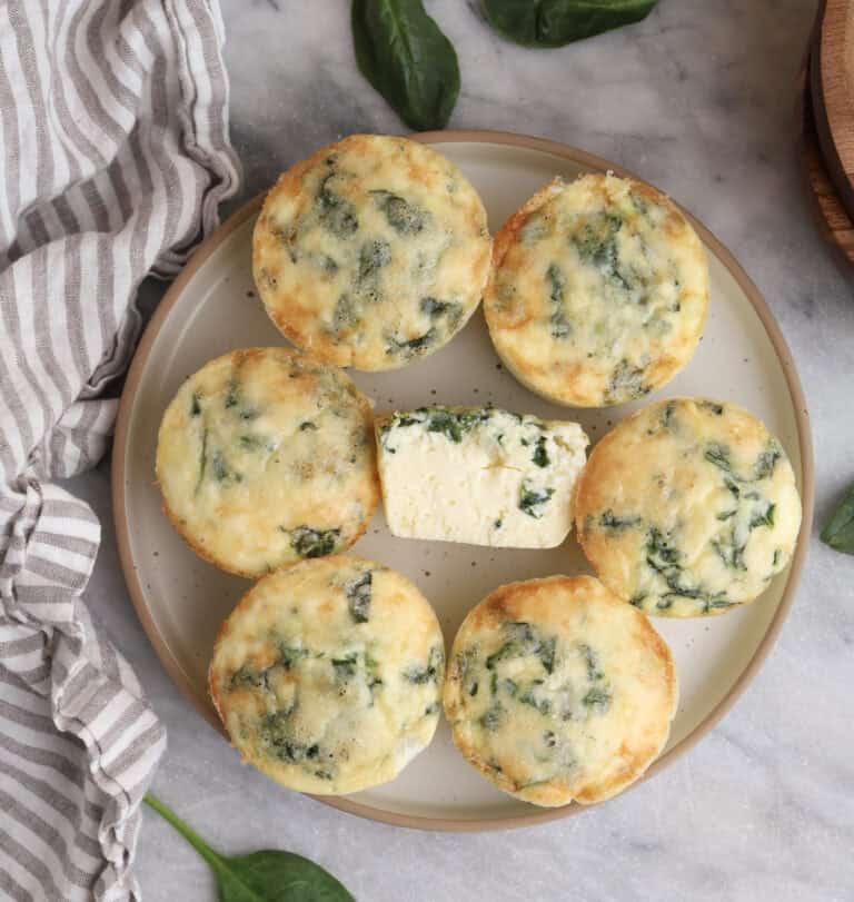 Cottage cheese egg bites on a plate with on in the middle cut open.