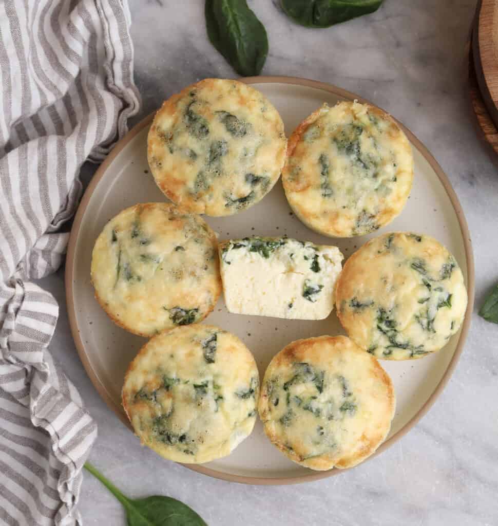 Cottage cheese egg bites on a plate with on in the middle cut open.