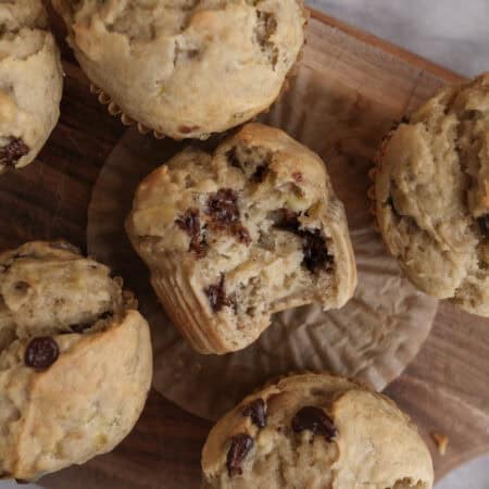 Banana Muffins with Chocolate Chips on a cutting board with one in the middle with a bite in it.
