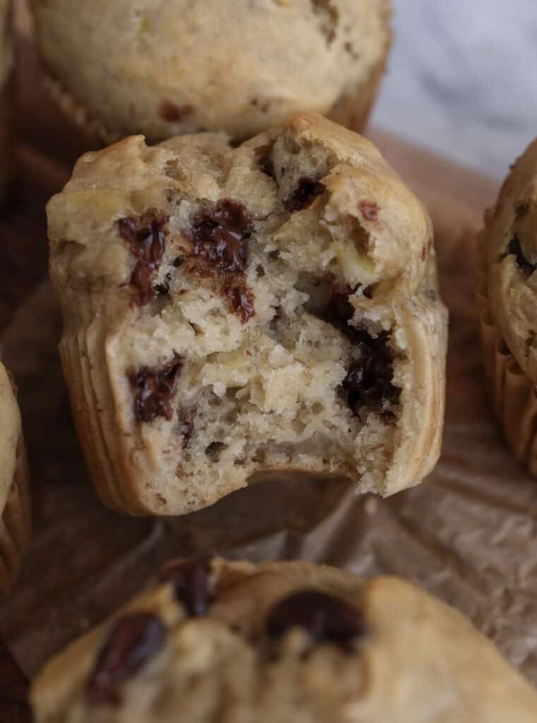 Banana Muffins with Chocolate Chips on a cutting board with one in the middle with a bite in it.