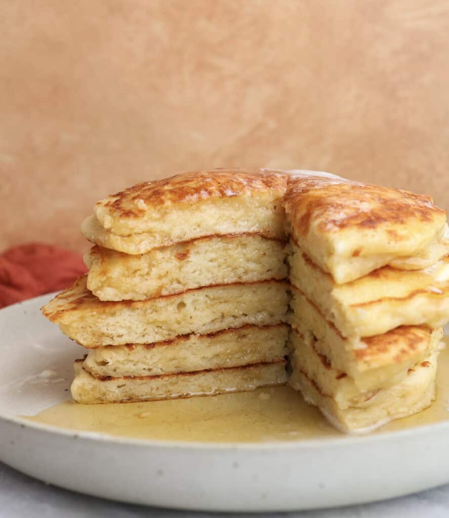 A stack of Greek yogurt pancakes cut into with maple syrup.