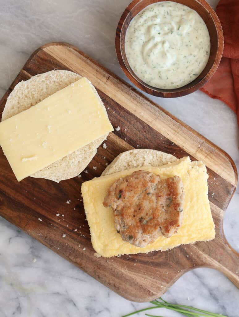 The egg, sausage and cheese sandwich on a cutting board, open faced.