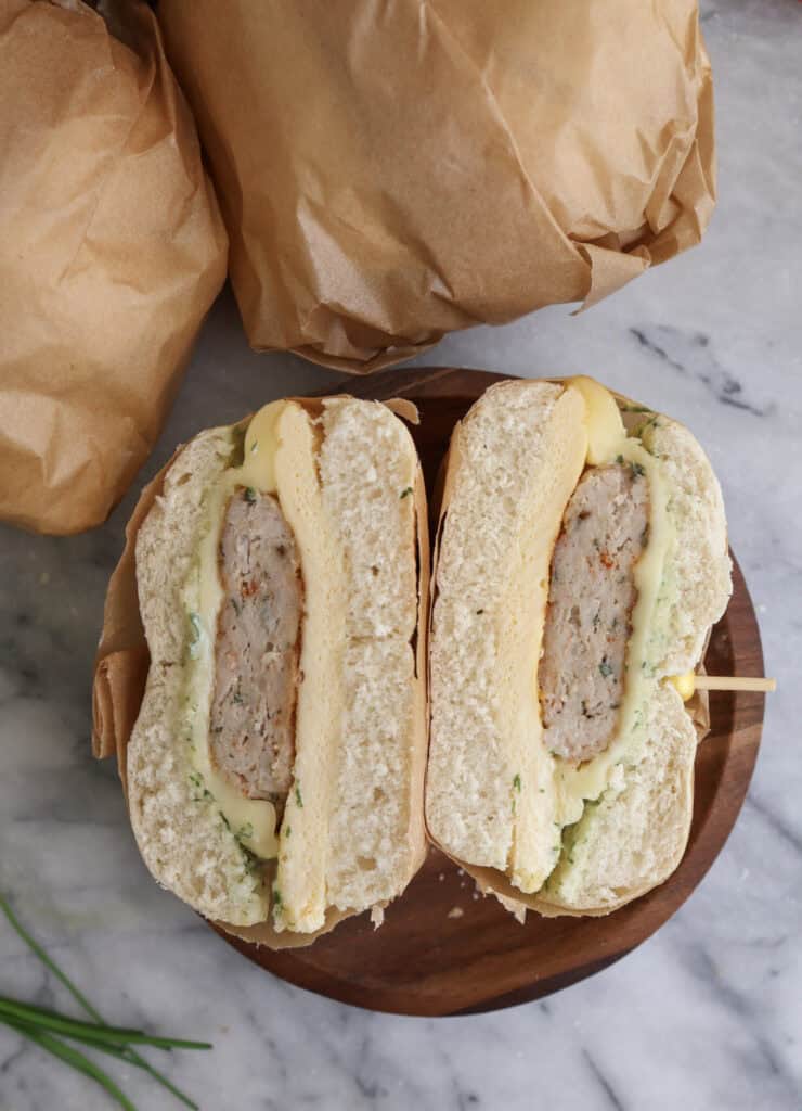 The freezer friendly breakfast sandwich cut up, showing the layers of cheese, egg and chicken sausage.