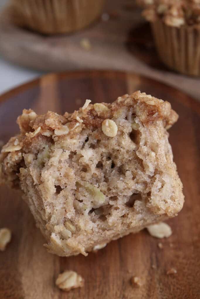 Apple oat muffin a wood plate with a bite taken out.
