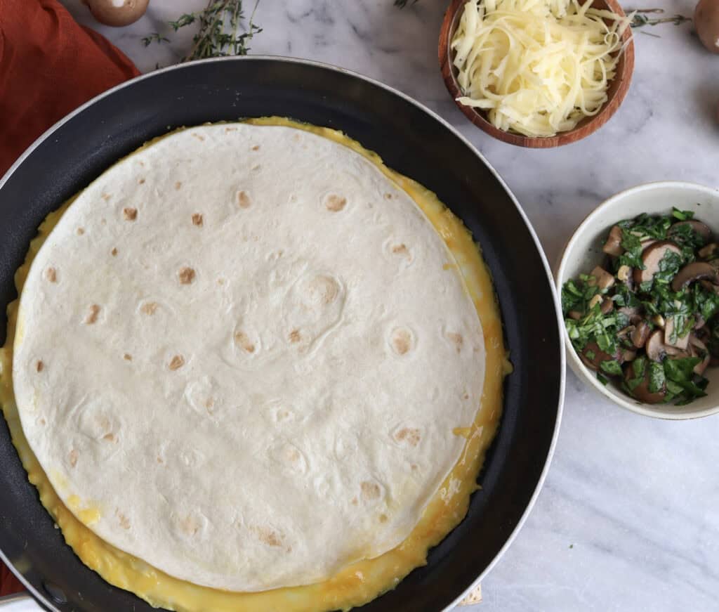 Eggs and tortilla in a skillet to make the egg wrap.