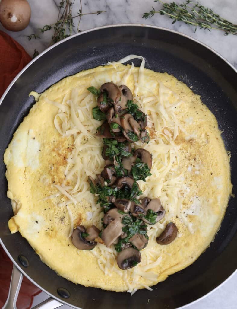 Mushrooms, spinach and thyme in the center of the egg wrap in the skillet.