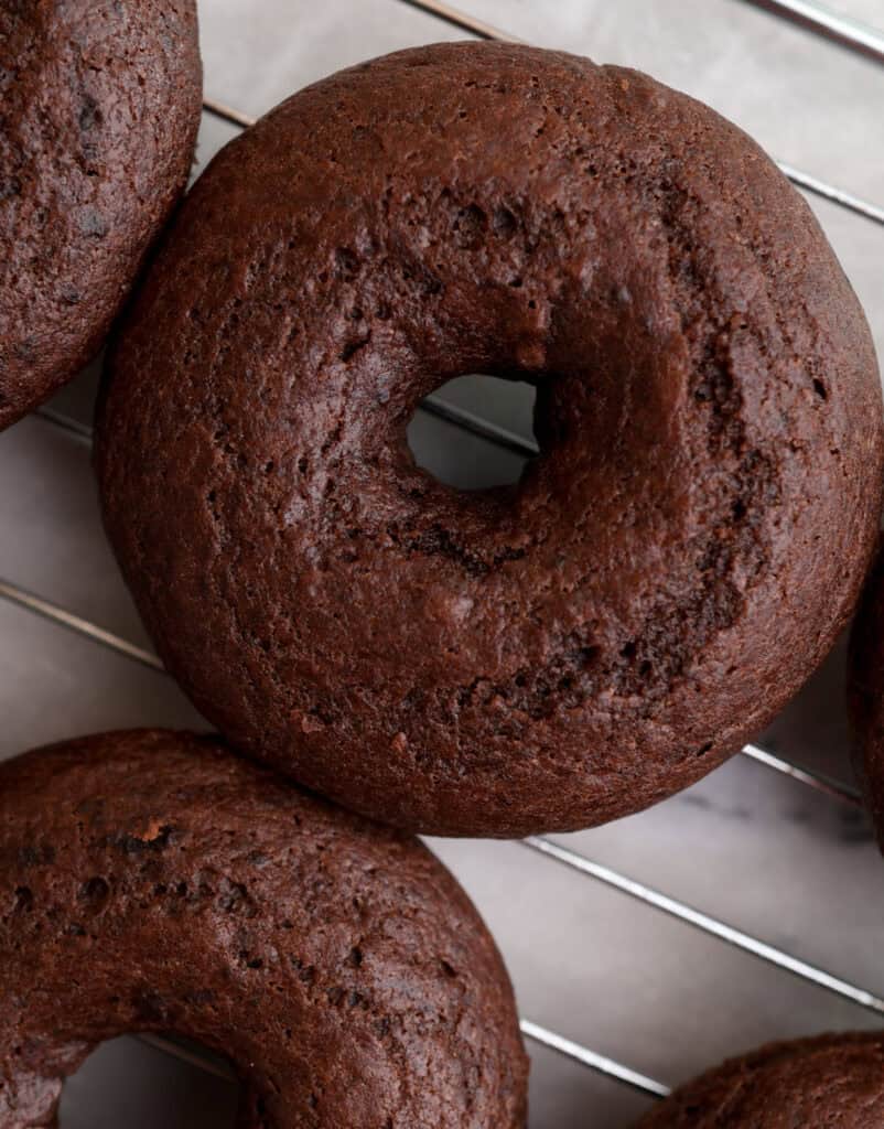 Freshly baked chocolate donut on a cooling rack.