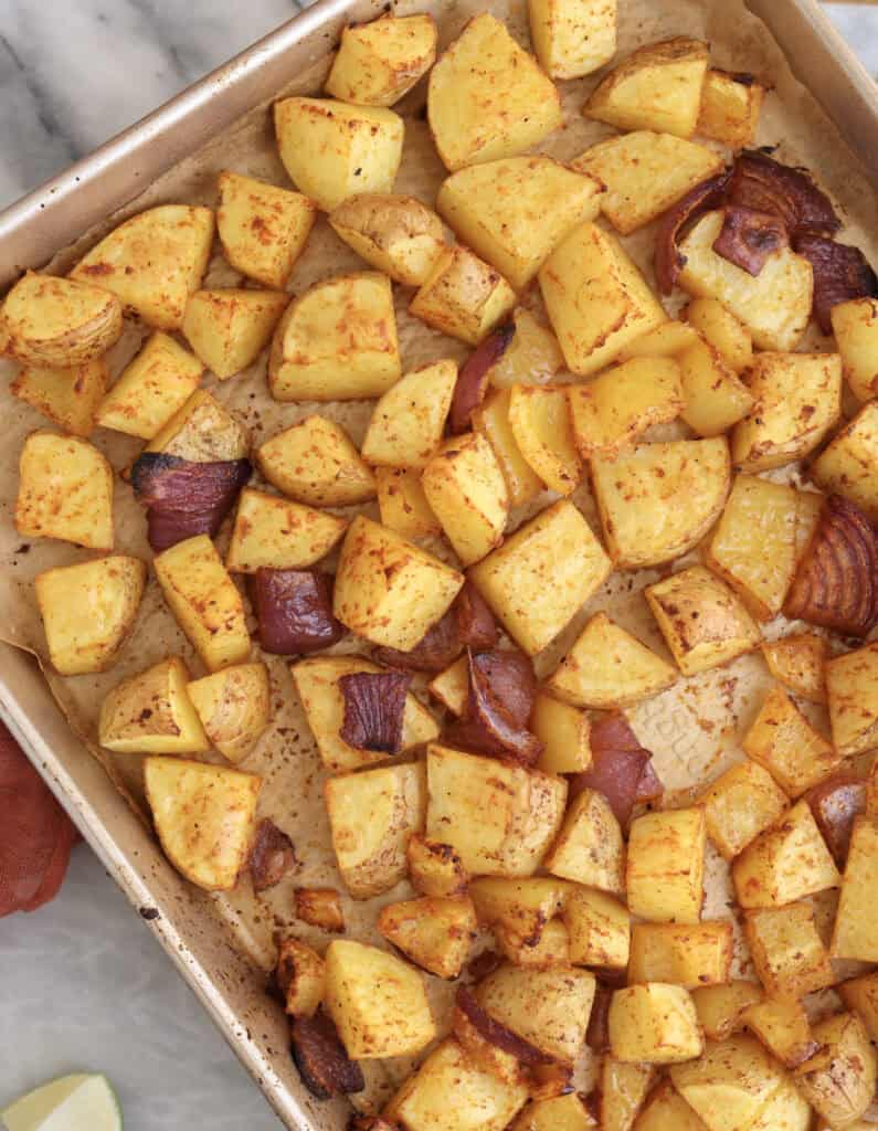 Roasted potatoes, onions, and bell pepper on baking sheet right from the oven.