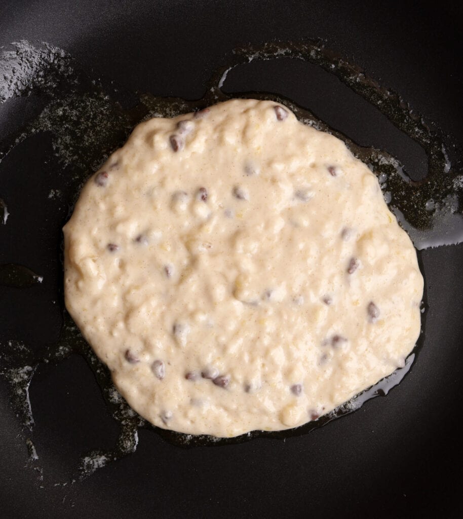 Banana pancake batter in the skillet cooking.