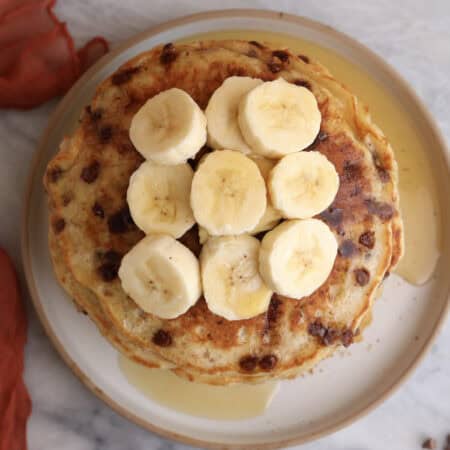 Overhead shot of a stack of banana pancakes with sliced bananas on top.