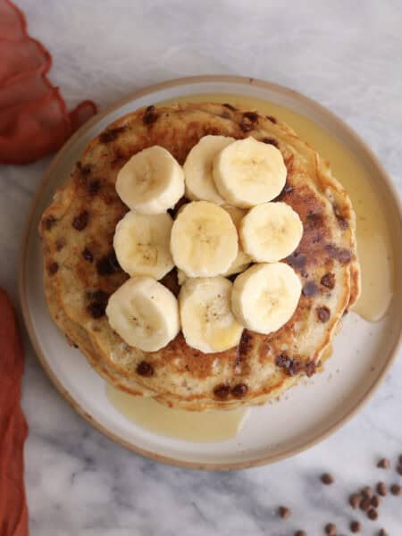 Overhead shot of a stack of banana pancakes with sliced bananas on top.