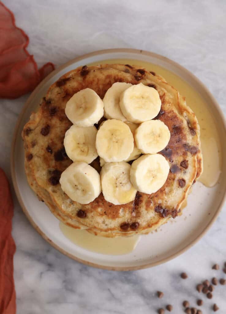 Overhead shot of a stack of banana pancakes with sliced bananas on top.