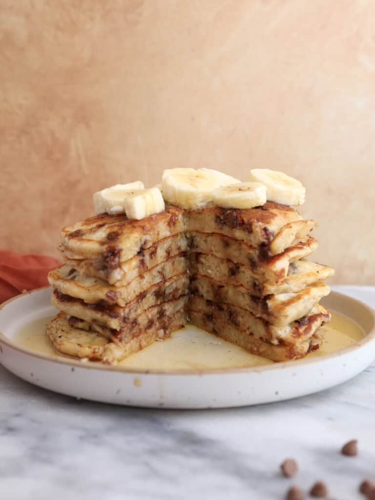 A stack of banana pancakes cut into, showing the melty chocolate chips and fluffy inside.