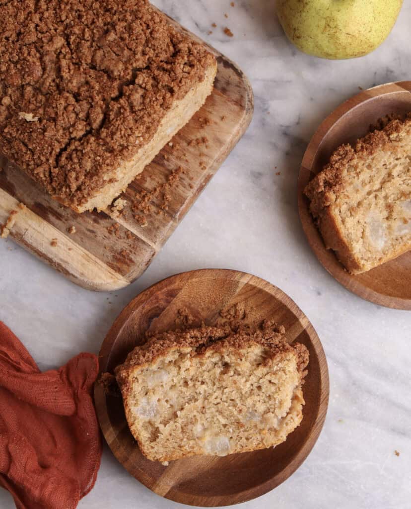 Pear bread on a wood cutting board  with two wood plate with a slice of pear bread. 