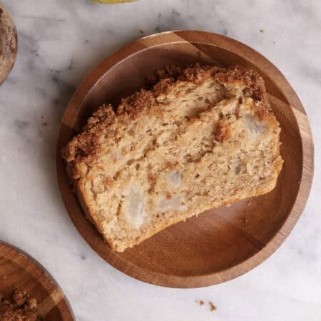 A slice of pear bread on a wood plate.
