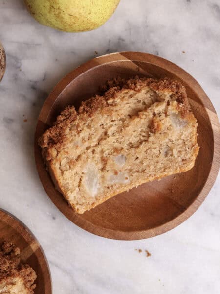 A slice of pear bread on a wood plate.