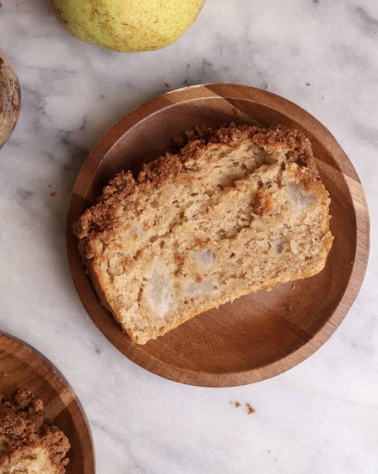 A slice of pear bread on a wood plate.