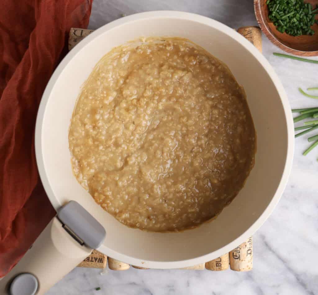 Cooked rolled oats in pan to make the savory oatmeal bowls.