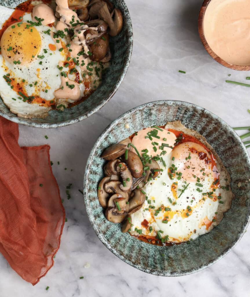 Two Savory oatmeal bowls loaded with oatmeal, fried egg, mushrooms and a homemade sriracha mayo.