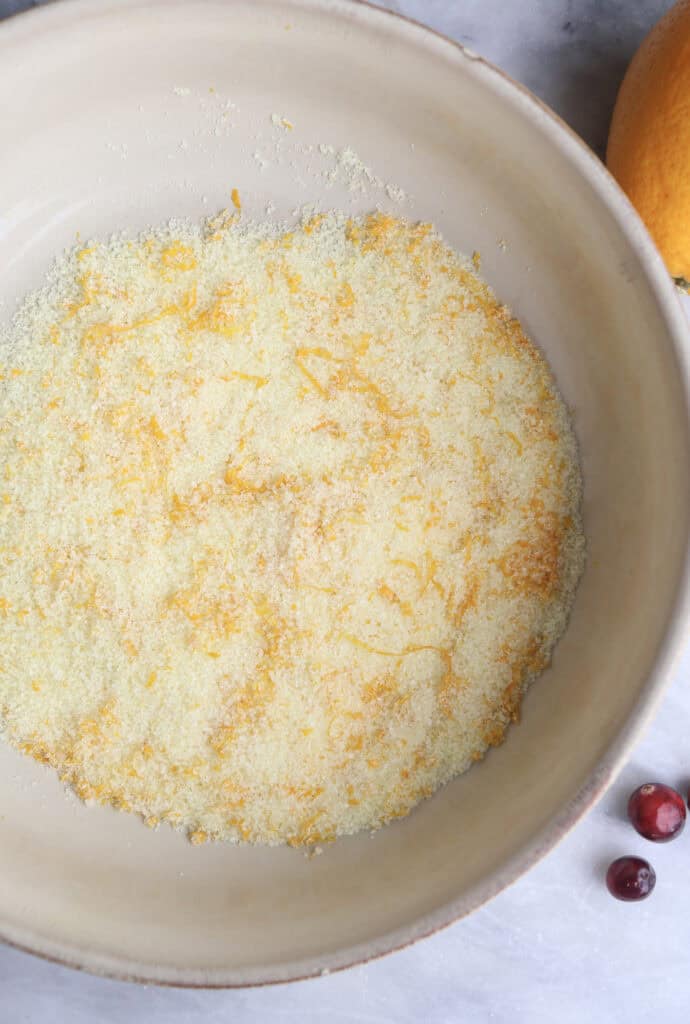 The sugar and orange zest in a bowl after rubbing together to release the orange oils.
