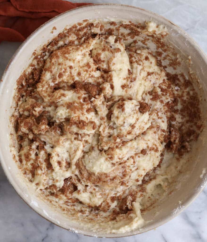 The cinnamon roll muffin batter with the cinnamon sugar gently folded in, showing the streaks of cinnamon sugar.