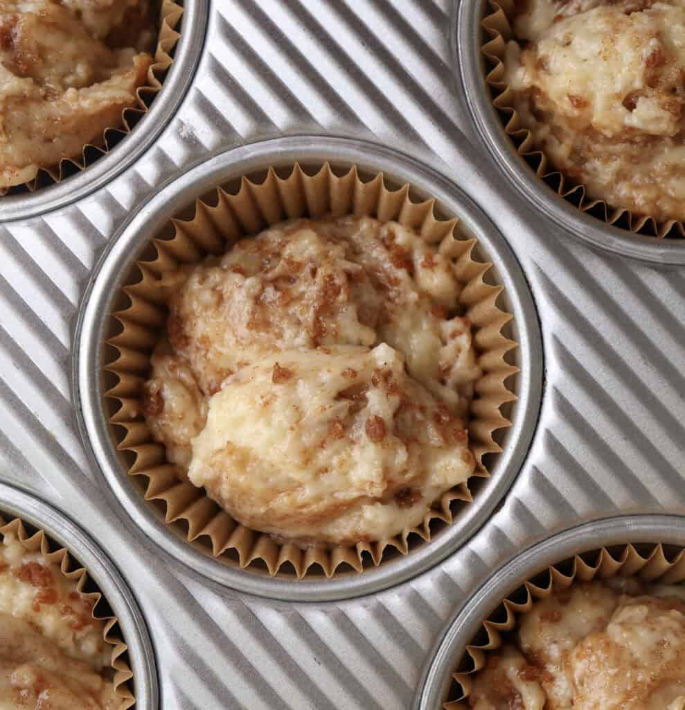 Cinnamon roll muffin batter into a muffin tin before being baked.