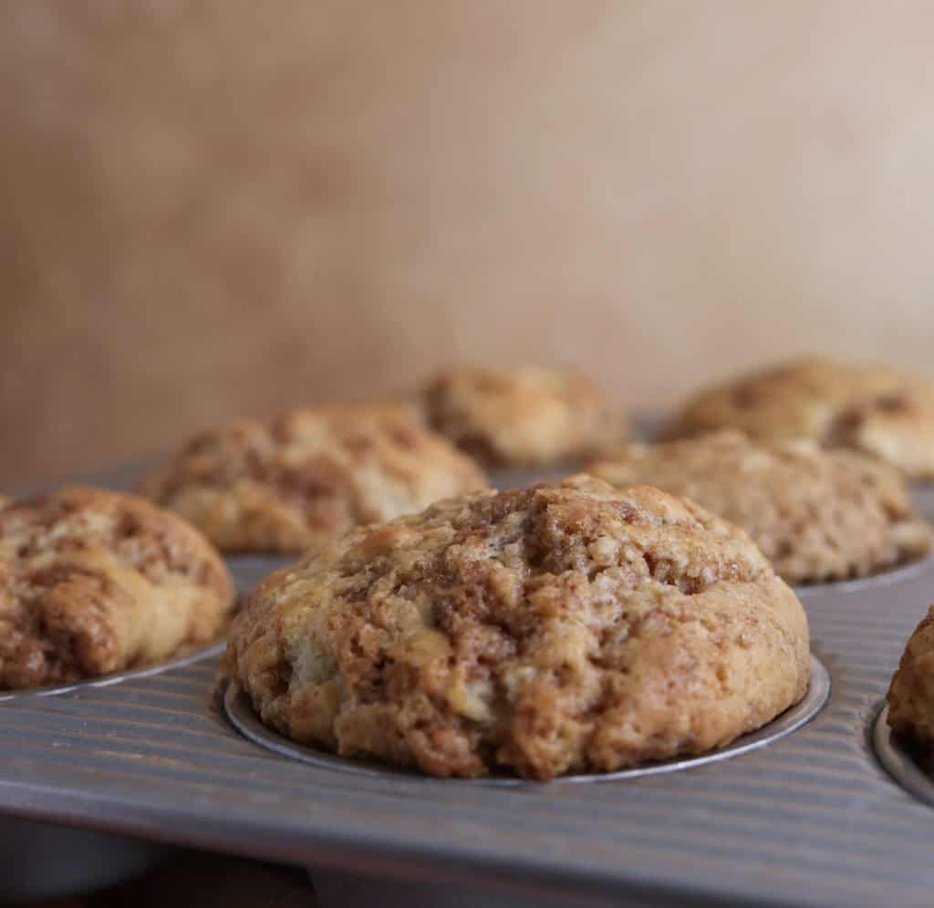 Side view of freshly baked cinnamon roll muffins still in the muffin tin.