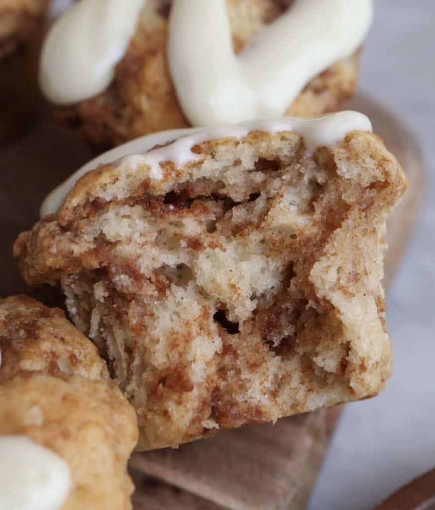 Up close shot of the cinnamon roll muffin with a bite, showing the cinnamon sugar swirls inside.